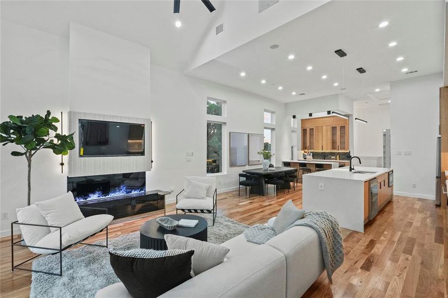 Living room featuring a towering ceiling, ceiling fan, light hardwood / wood-style floors, and sink