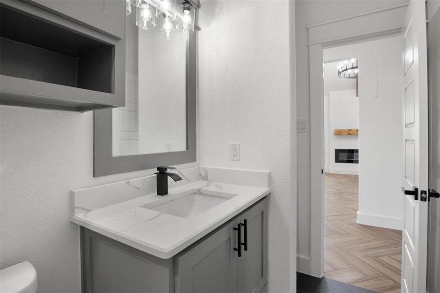 Bathroom with toilet, vanity, and parquet floors