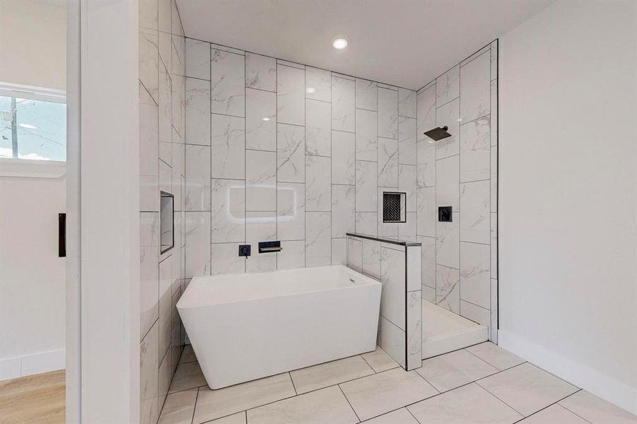Bathroom with tile flooring, shower with separate bathtub, and tile walls