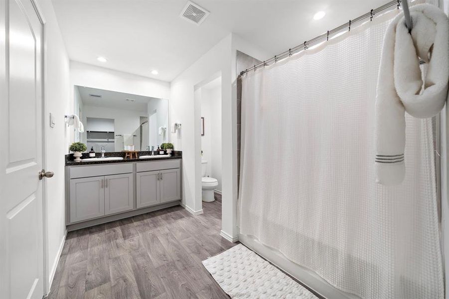 Primary bathroom features double-sink, Luxury vinyl flooring, and a tile tub/shower combo.