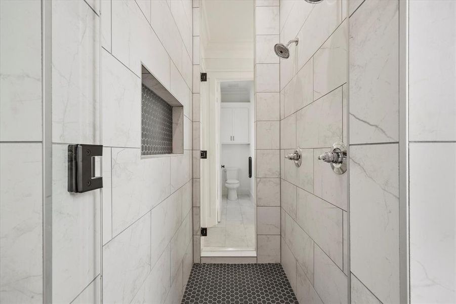 Bathroom featuring tile walls, toilet, and tiled shower