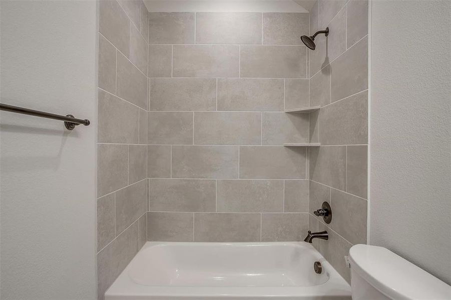 Bathroom with tiled shower / bath combo and toilet