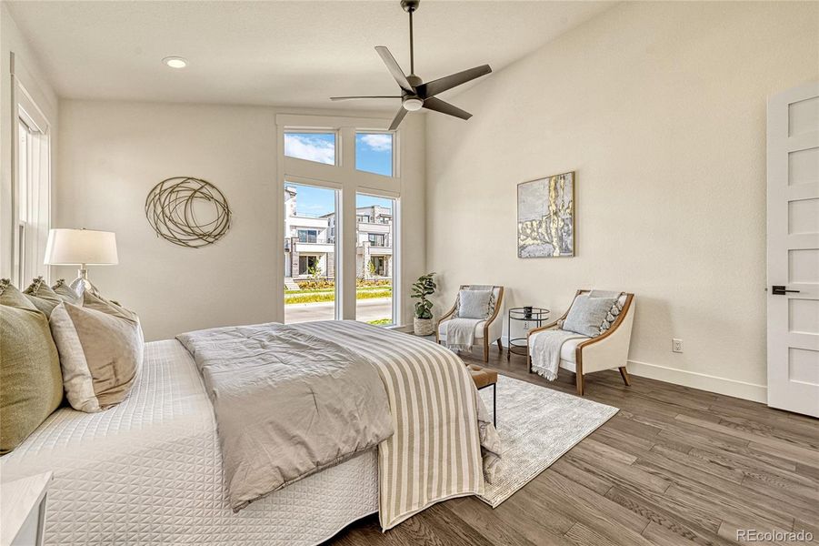 High, vaulted ceilings with a ceiling fan, luxury vinyl plank flooring and multiple large windows allowing light to shine in.