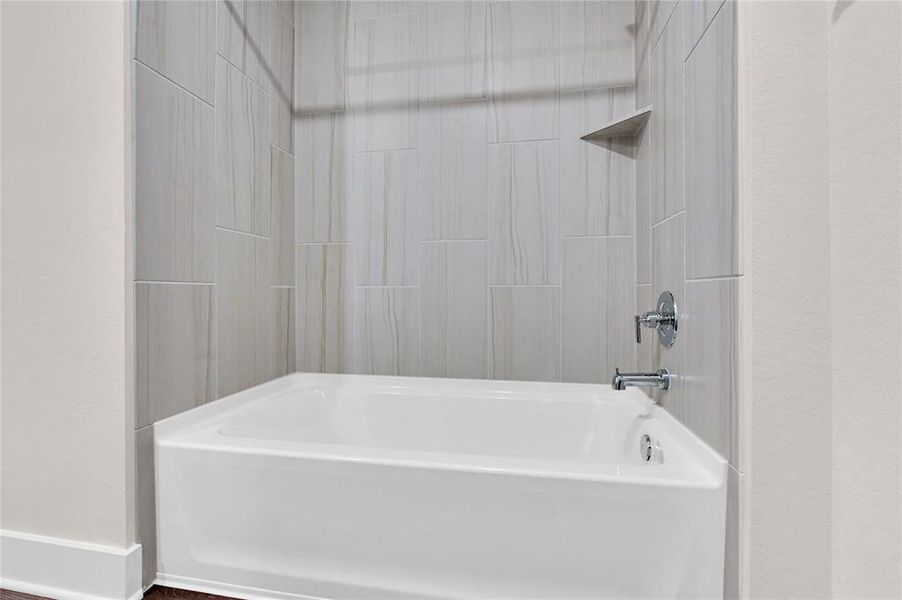 The tub/shower combo in the secondary bathroom atop the second floor is lined with a modern tile tub surround and nickel fixtures.