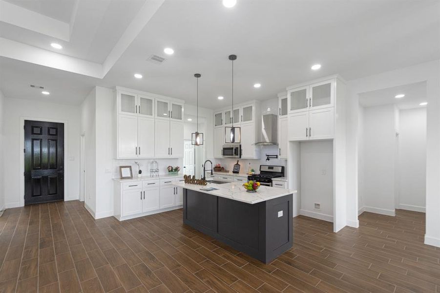 Modern kitchen with large island.  Upgraded self-closing custom wood cabinets with glass to ceiling.  Plenty of recessed lighting and modern fixtures.  This is a Chefs delight.