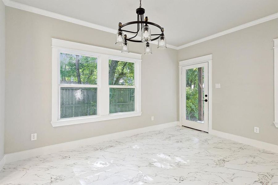 Spare room with a notable chandelier, ornamental molding, and a wealth of natural light