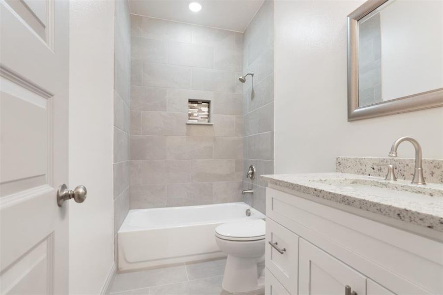 Full bathroom with tile floors, vanity, toilet, and tiled shower / bath combo