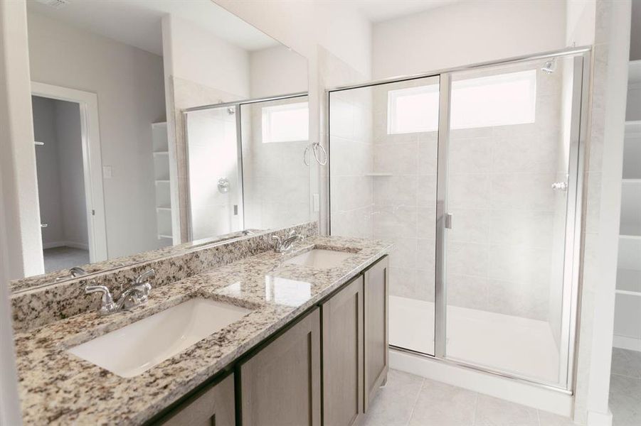Bathroom featuring dual vanity, a shower with door, and tile patterned floors