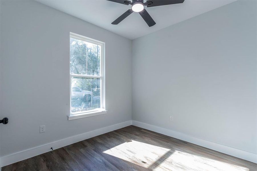 Empty room with ceiling fan and dark hardwood / wood-style floors