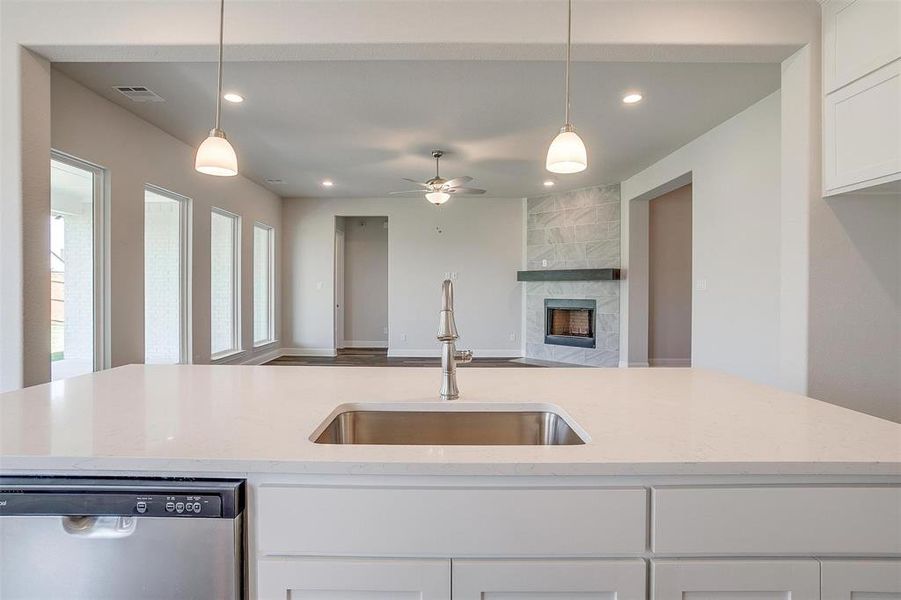 Kitchen with sink, dishwasher, light stone countertops, and a fireplace