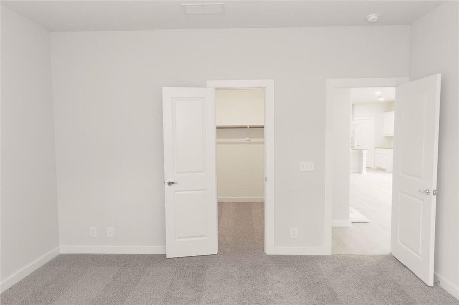Unfurnished bedroom featuring a closet, light carpet, and a spacious closet