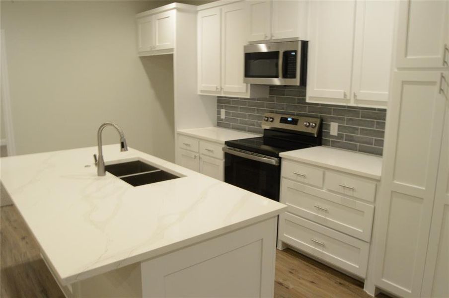 Kitchen has beautiful quartz countertops appliances with stainless steel finishes