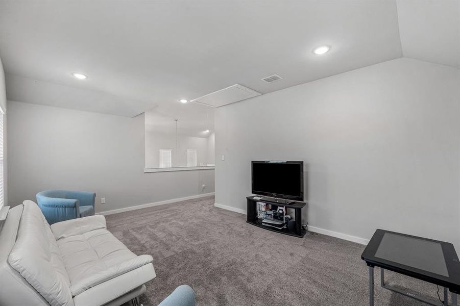 Carpeted living room featuring lofted ceiling