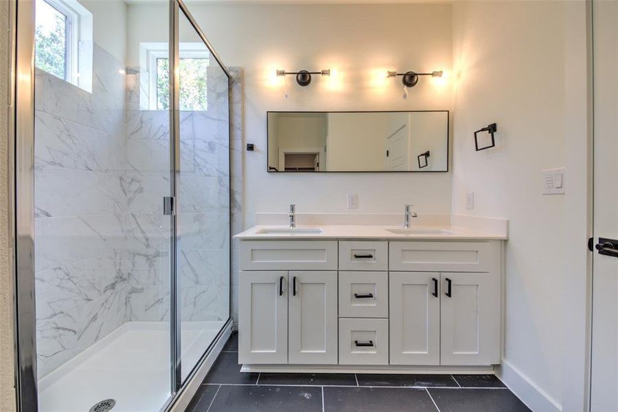 Double-sink vanity, storage drawers and ceramic tile flooring at primary bath