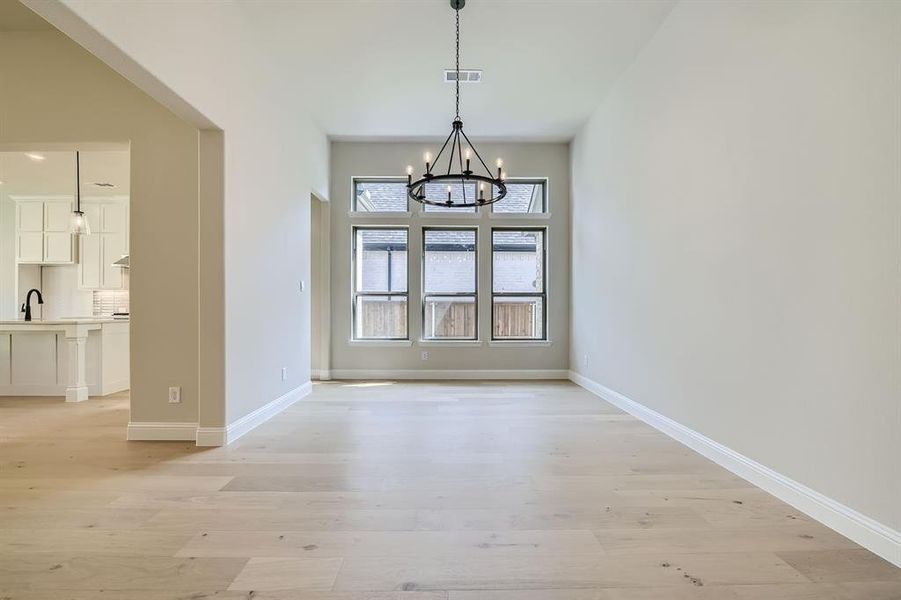 Unfurnished dining area with sink, light hardwood / wood-style flooring, and a chandelier