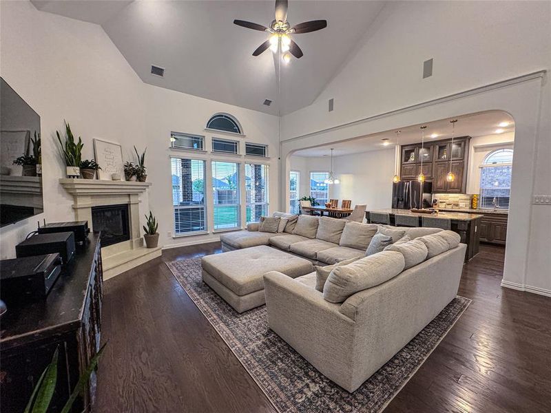 Living room with ceiling fan, high vaulted ceiling, and dark hardwood / wood-style flooring