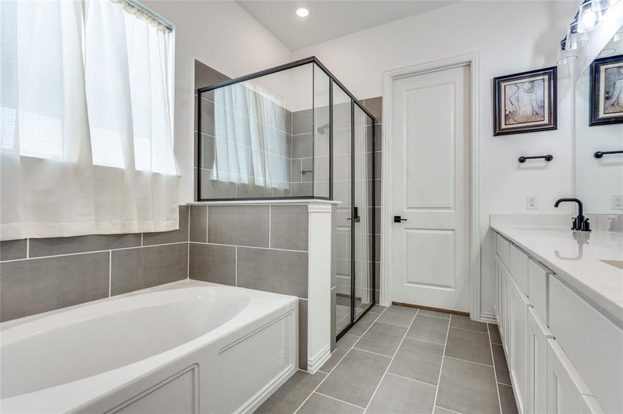 Bathroom featuring plus walk in shower, tile patterned floors, and vanity