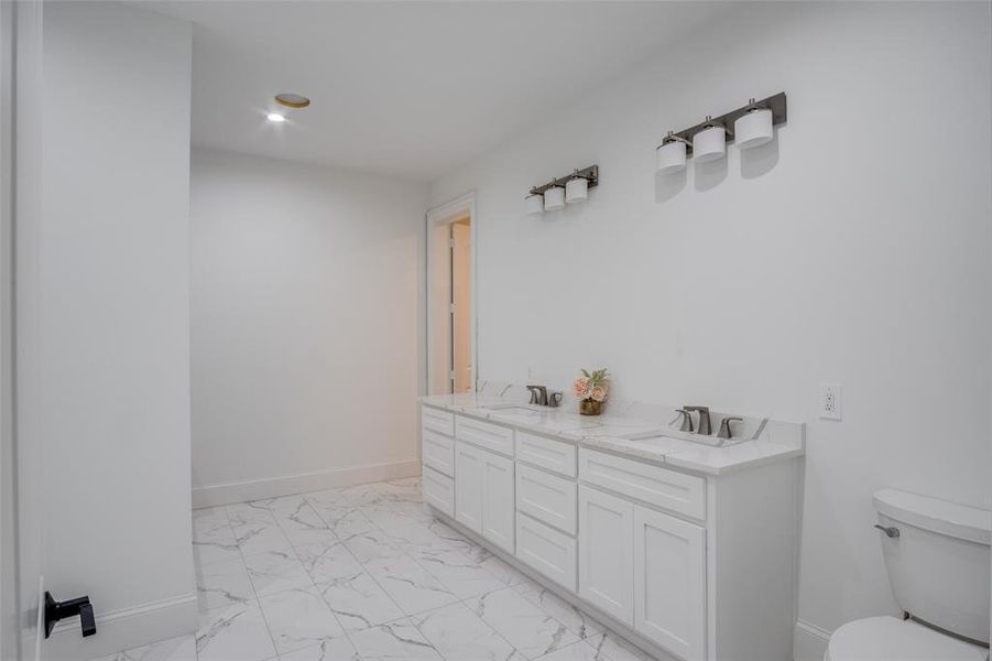 Bathroom featuring toilet, tile patterned flooring, and double vanity