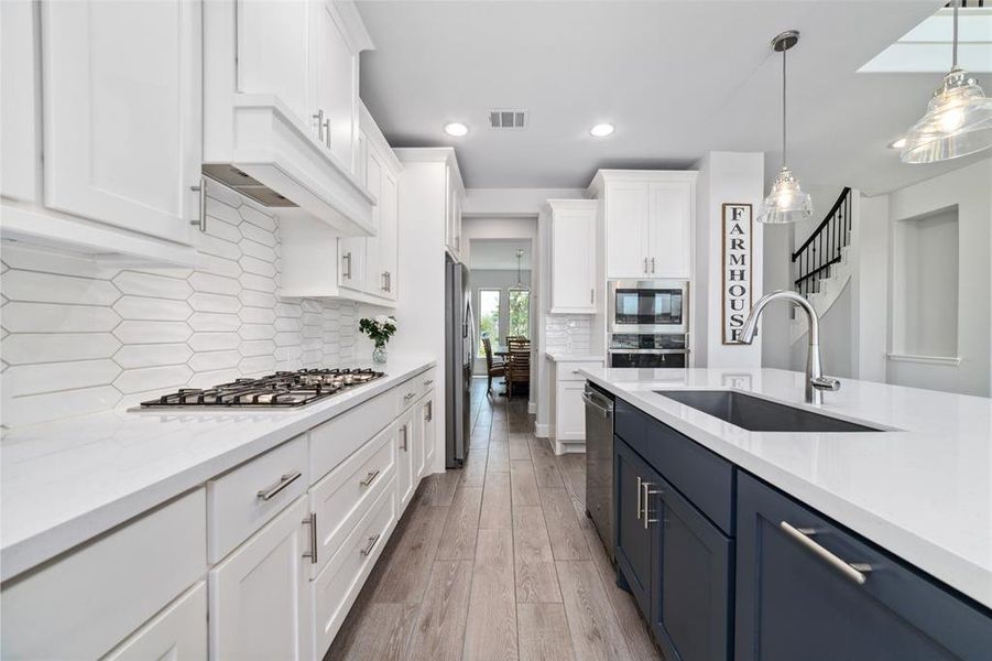 This modern, spacious kitchen with white upper cabinetry and contrasting navy lower cabinets, complemented by a sleek Quartz Countertop.