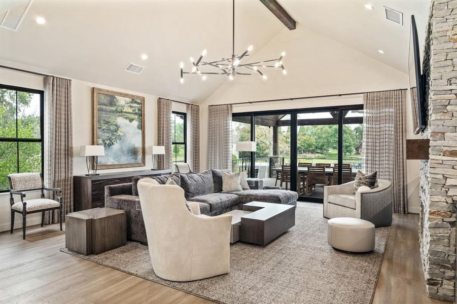 Living room featuring beamed ceiling, a healthy amount of sunlight, light hardwood / wood-style flooring, and an inviting chandelier