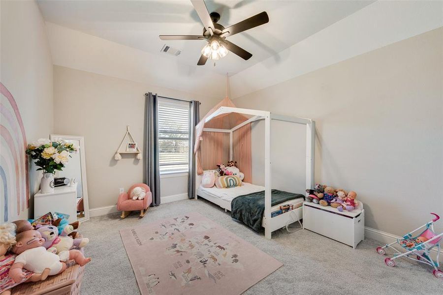 Bedroom with ceiling fan, lofted ceiling, and light carpet