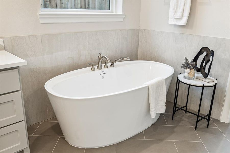 Unwind in style in the lavish primary bath, featuring a luxurious soaking tub tucked underneath a window for subtle natural light.