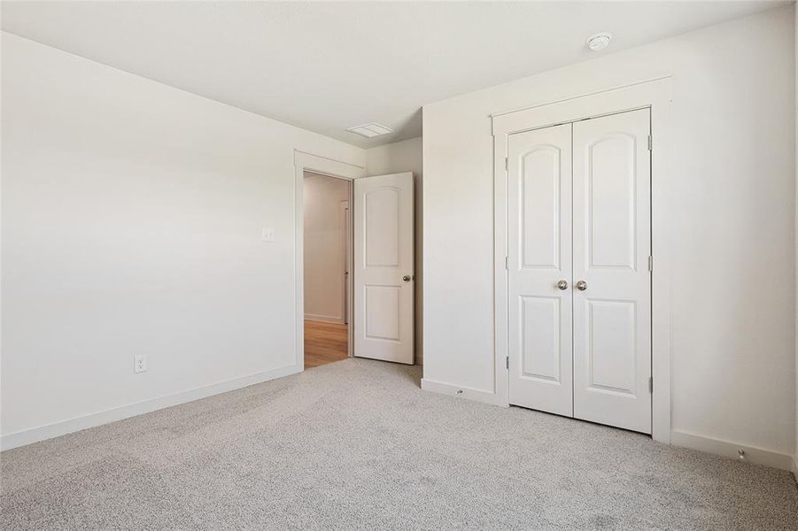 Unfurnished bedroom with light carpet and a closet