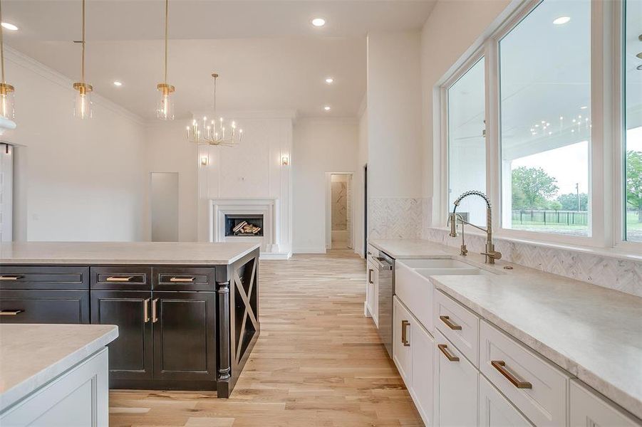 Kitchen featuring pendant lighting, white cabinets, light wood-type flooring, and crown molding