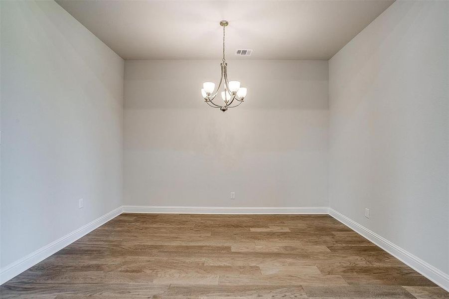 Spare room featuring an inviting chandelier and hardwood / wood-style flooring