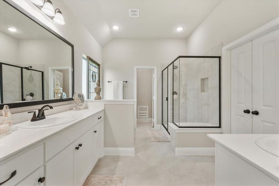 Bathroom with a shower with shower door, vanity, tile patterned floors, and lofted ceiling