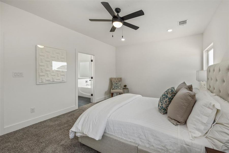 Carpeted bedroom featuring ensuite bathroom and ceiling fan