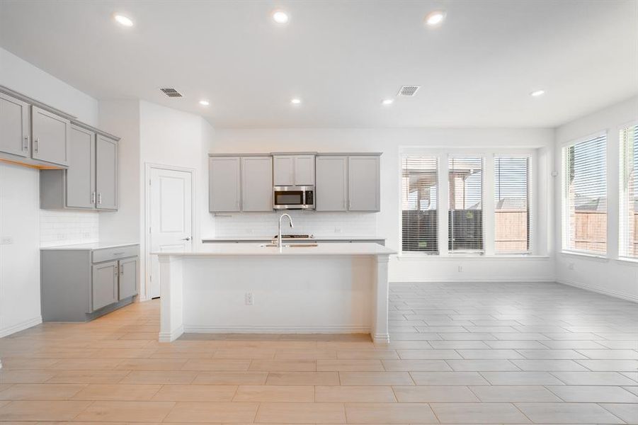 Kitchen with gray cabinetry and a kitchen island with sink