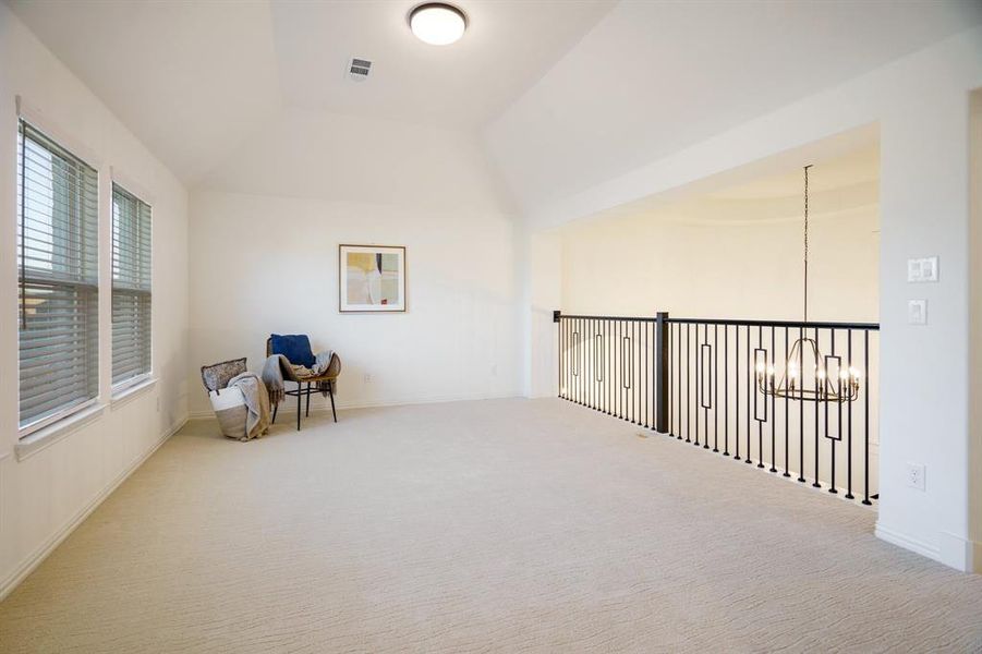 Sitting room featuring carpet flooring, lofted ceiling, and a chandelier