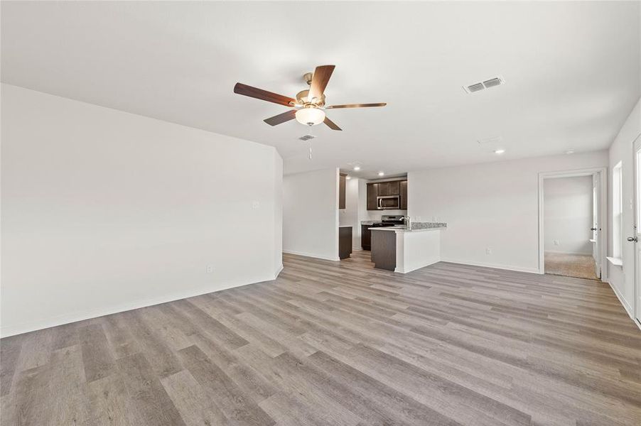 Unfurnished living room featuring ceiling fan and light hardwood / wood-style flooring