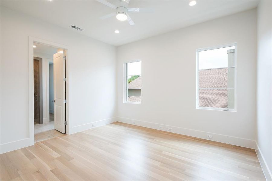 Empty room with ceiling fan and light hardwood / wood-style floors