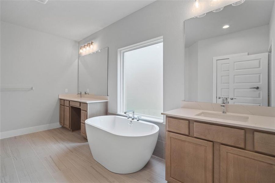 This primary bathroom is definitely move-in ready! Featuring a freestanding tub for soaking after a long day, stained cabinets with countertops, spacious walk-in closet with shelving, high ceilings, custom paint, sleek and dark modern finishes.