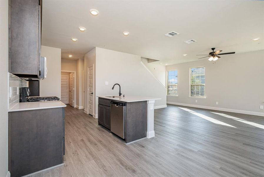 Kitchen featuring dishwasher, sink, range, light hardwood / wood-style floors, and tasteful backsplash