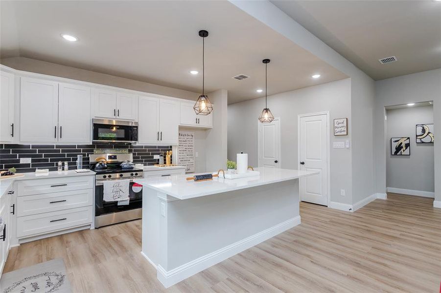 Kitchen with appliances with stainless steel finishes, a center island, and white cabinets