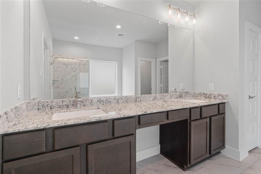 This primary bathroom is definitely move-in ready! Featuring stained cabinets with dual vanity countertop, spacious walk-in closet with shelving, high ceilings, custom paint, and sleek modern finishes.