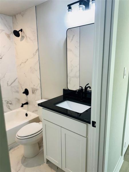 Full bathroom featuring tiled shower / bath, vanity, and toilet