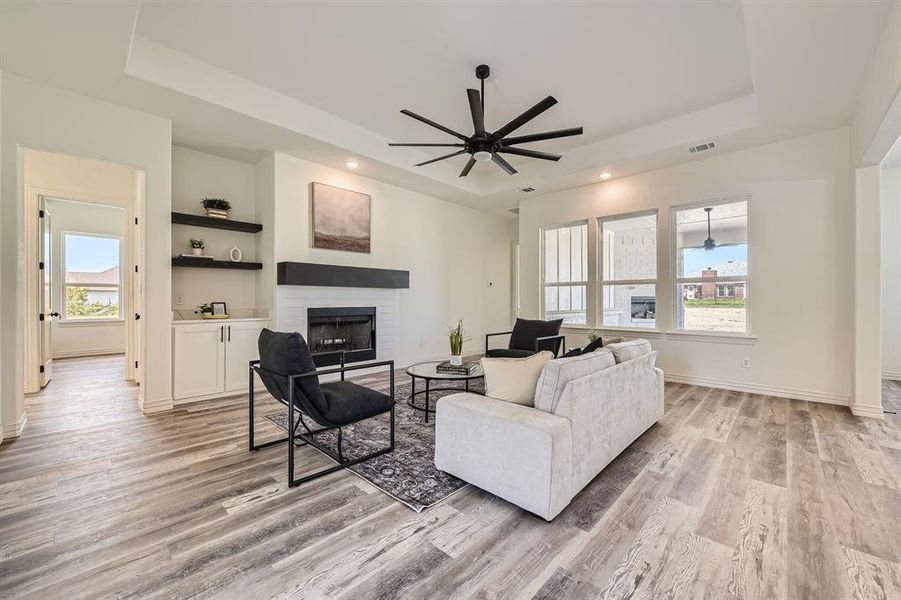 Living room with light hardwood / wood-style floors, plenty of natural light, ceiling fan, and a brick fireplace