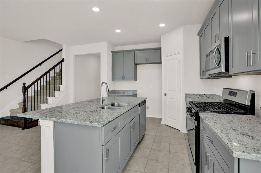 Kitchen featuring sink, a kitchen island with sink, light tile floors, and stainless steel appliances