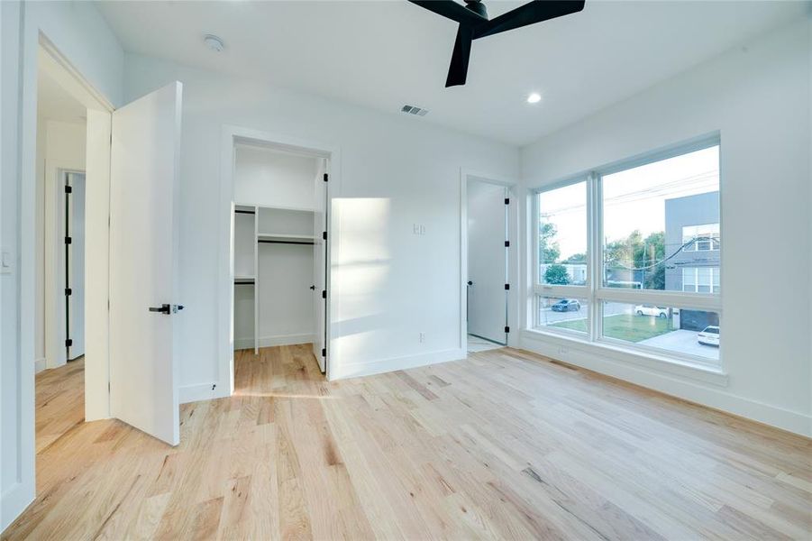 Unfurnished bedroom featuring a closet, a walk in closet, light wood-type flooring, and ceiling fan