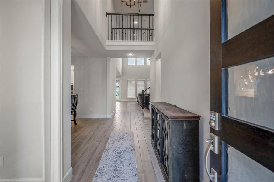 Walking in, you are greeted by a light and open space! The entryway is complete with beautiful light wood tile flooring that continues throughout the first floor into the main living areas making it easy to clean and maintain, 2 story ceilings, and a modern light fixture.