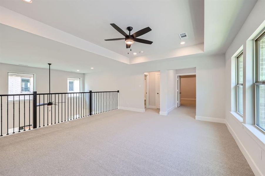 Carpeted spare room featuring ceiling fan and a raised ceiling