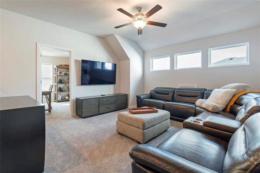 Living room with ceiling fan, light colored carpet, and lofted ceiling