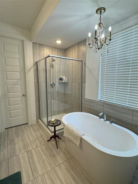 Bathroom with a textured ceiling, a chandelier, and separate shower and tub