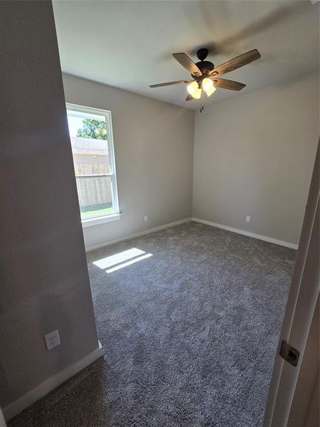 Empty room with dark carpet and ceiling fan