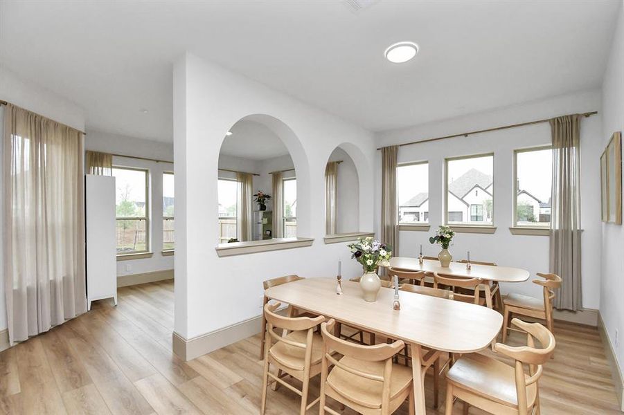 The dining area, adjacent to the kitchen, looks through to the sunroom/flex space.  The architecture of the pony wall with arches enhances the beauty of this space.