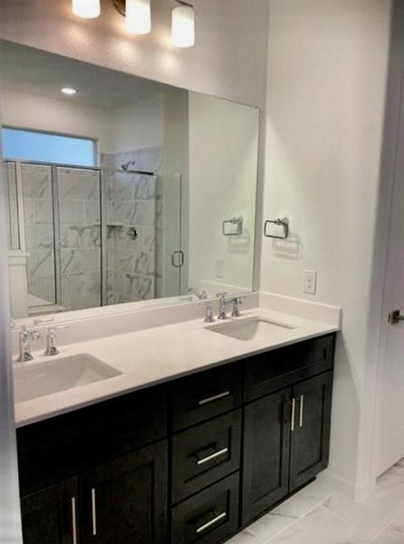 Primary bathroom featuring a beautiful shower, tile flooring, oversized vanity, and dual sinks